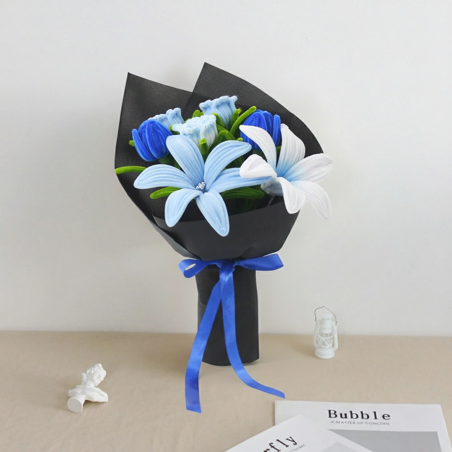 Bluence DIY bouquet featuring blue, white, and light blue lilies made from pipe cleaners, wrapped in sleek black paper with a royal blue ribbon.